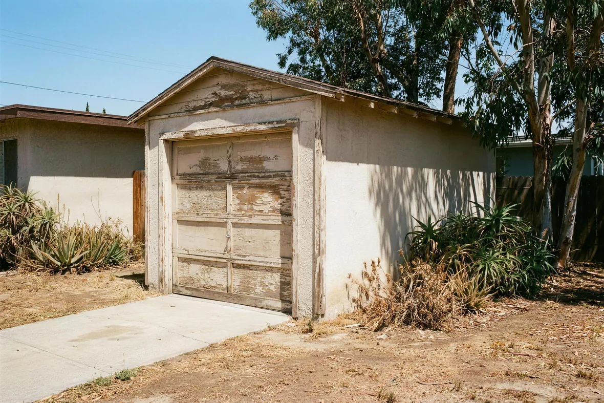 An older detached single-car garage with a weathered door and frame