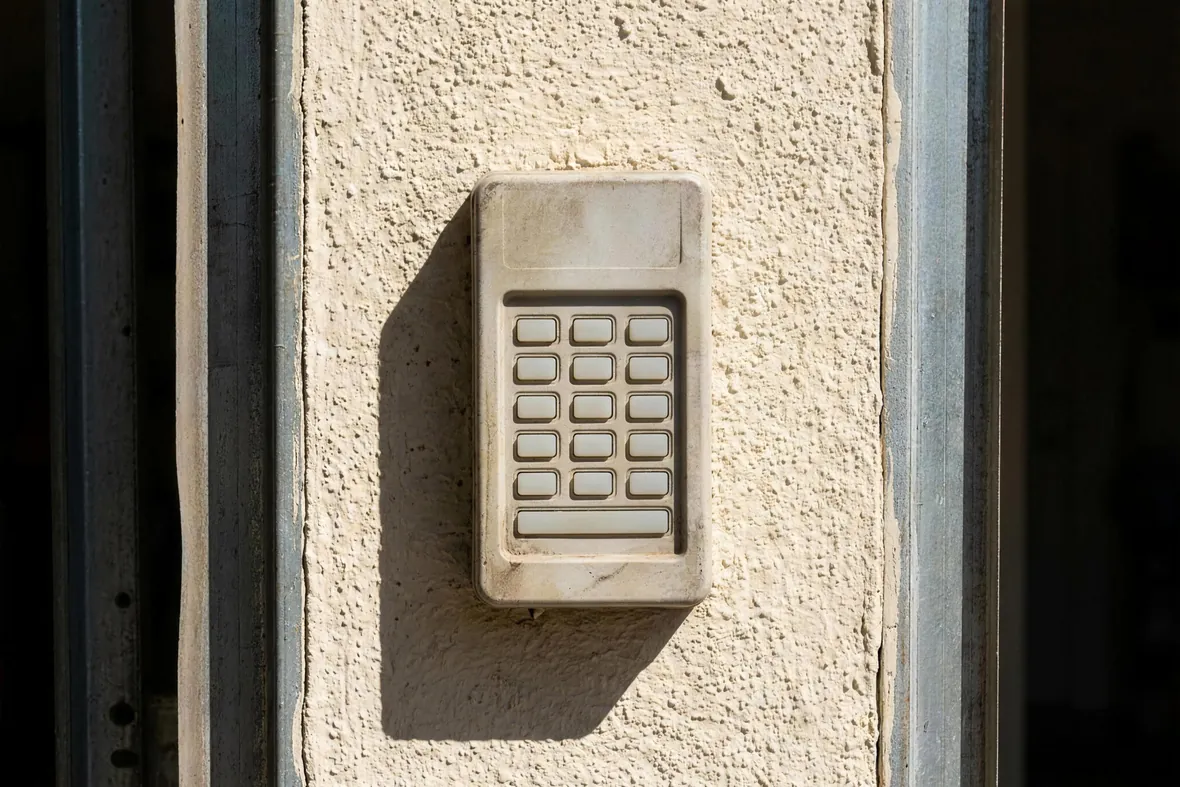 A wireless entry keypad mounted on the jamb beside a garage door
