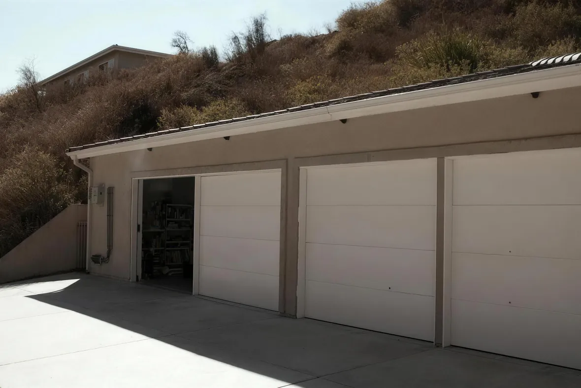 A residential street of tract homes at noon, deep shade under the eaves